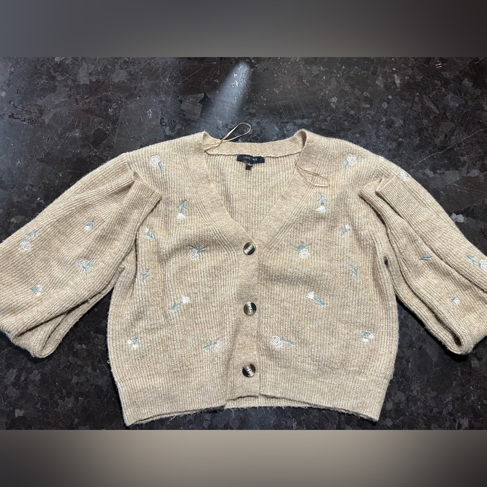 This is a tan cropped sweater with pink flowers and long sleeves. From Love Tree
